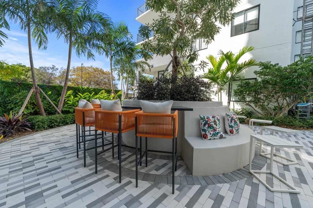 A patio with a table and chairs surrounded by greenery.