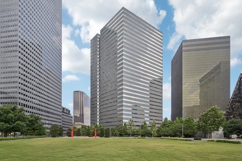 A cityscape with tall buildings and a green field in the foreground.