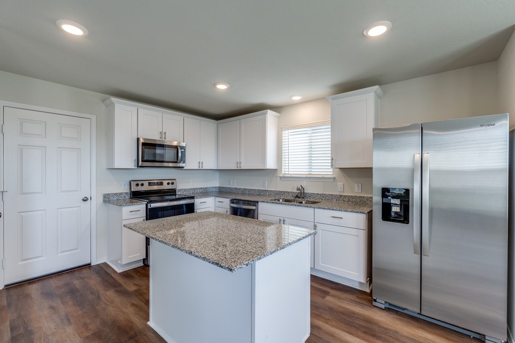 A kitchen with white cabinets and a granite island.