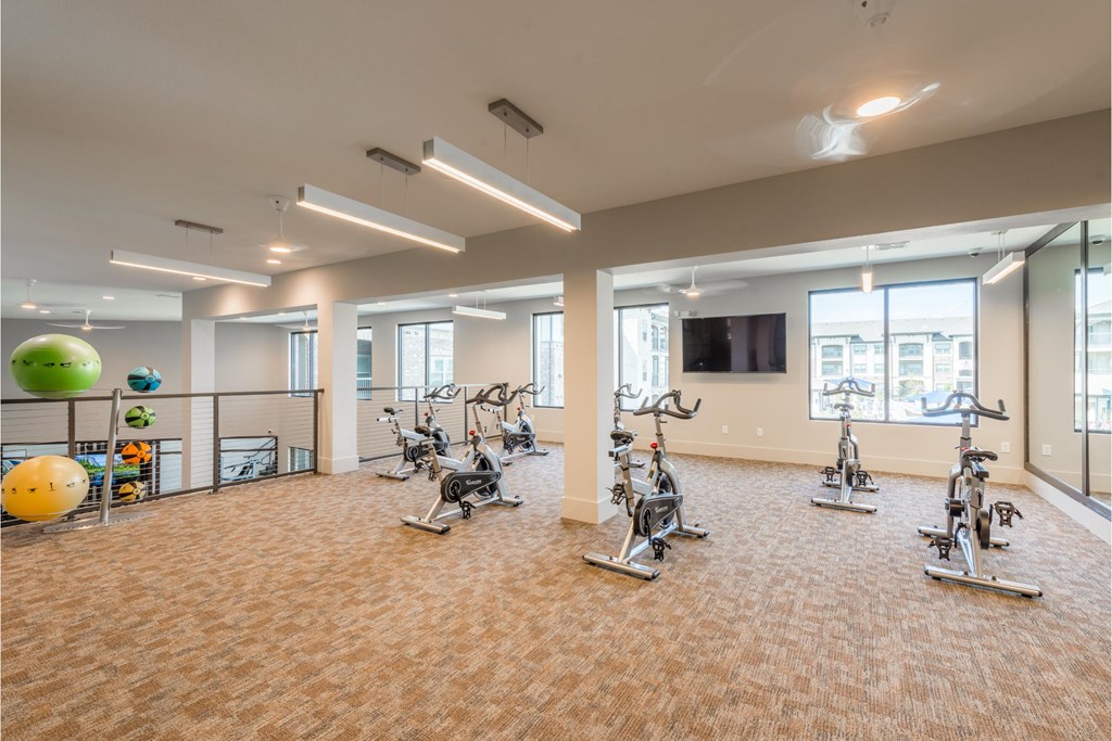 a gym with treadmills and exercise equipment in a large room with windows
