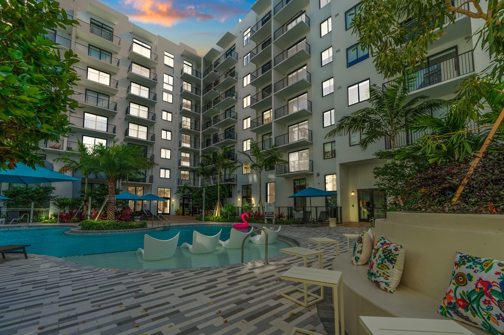 A pool area with a bench and a chair in front of a building.