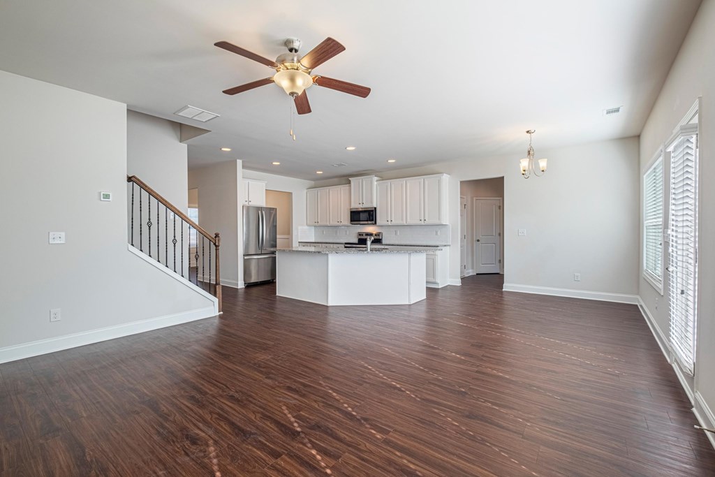 an empty living room and kitchen with a ceiling fan