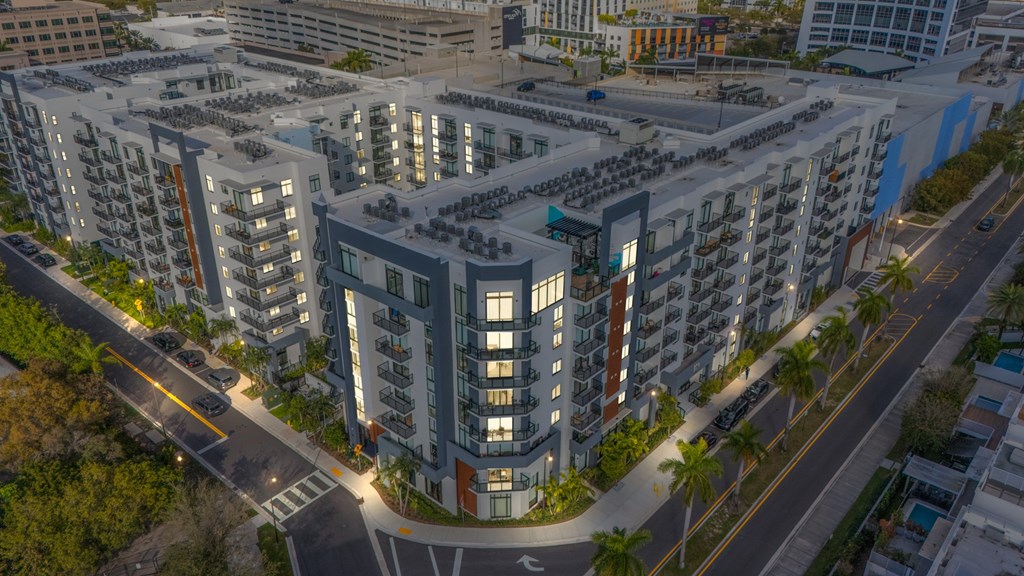 A modern apartment complex with a parking lot in front.