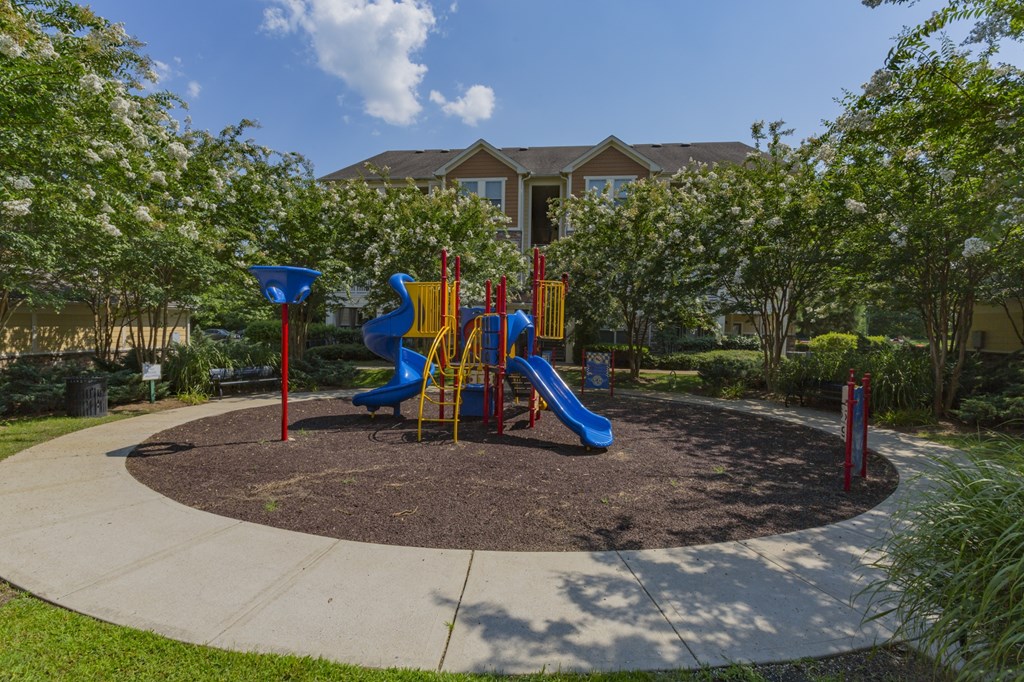 One, Two, And Three-bedroom Apartments In Hendersonville, TN - The Grove At Waterford Crossing - Playground With Slides And Climbing Equipment, And Surrounded by Trees and Grass.