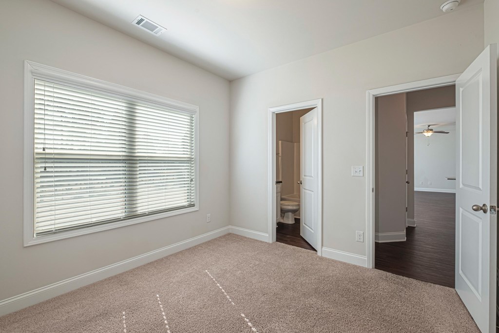 a bedroom with a large window and a door to a bathroom