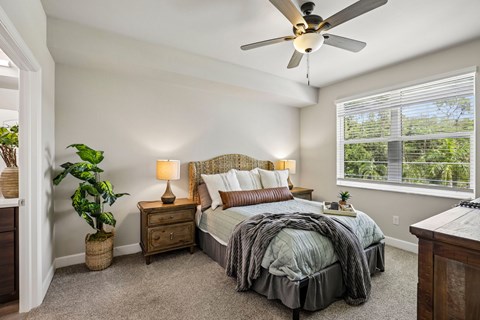 A bedroom with a bed, nightstand, and a ceiling fan.