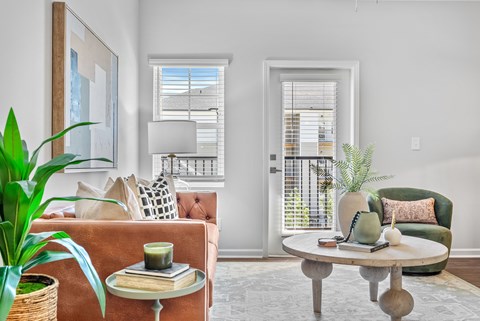 A living room with a brown sofa, a green armchair, a wooden coffee table, and a large painting on the wall.