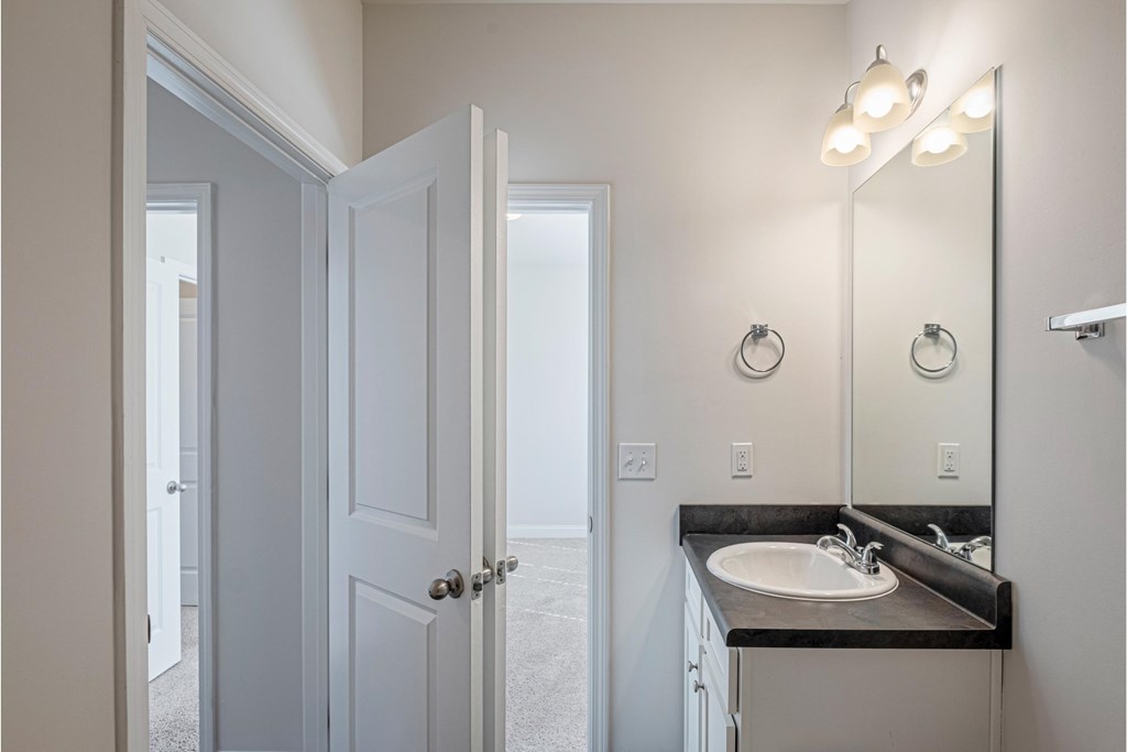 a bathroom with a sink and a mirror and an open door