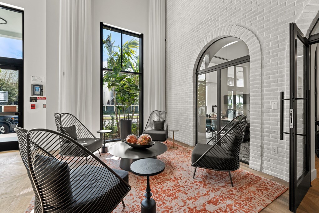 A black chair with a bowl of fruit on a table in front of a window.