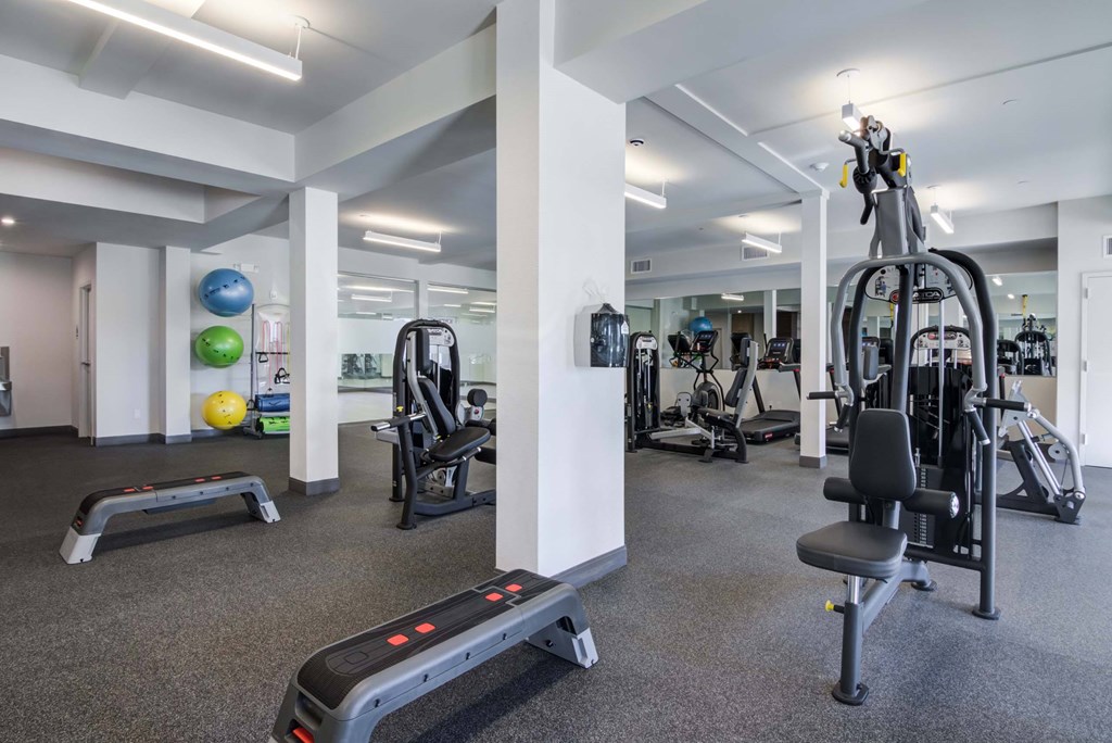 A gym with a variety of equipment including treadmills, weights, and exercise machines.