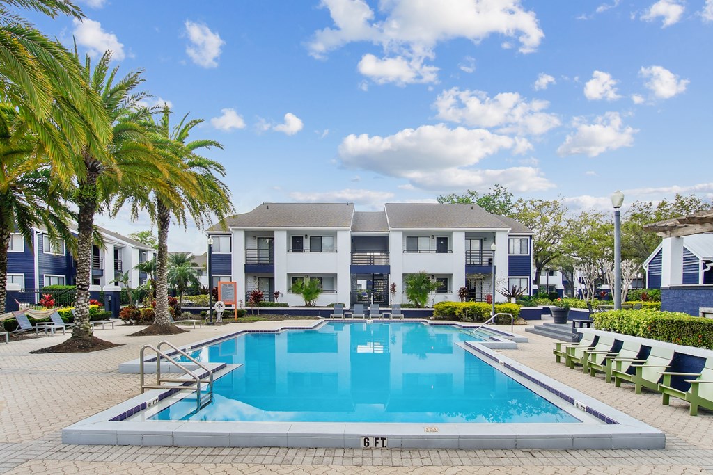 a swimming pool in front of a building with a resort style pool