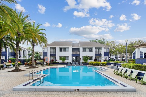 a swimming pool in front of a building with a resort style pool