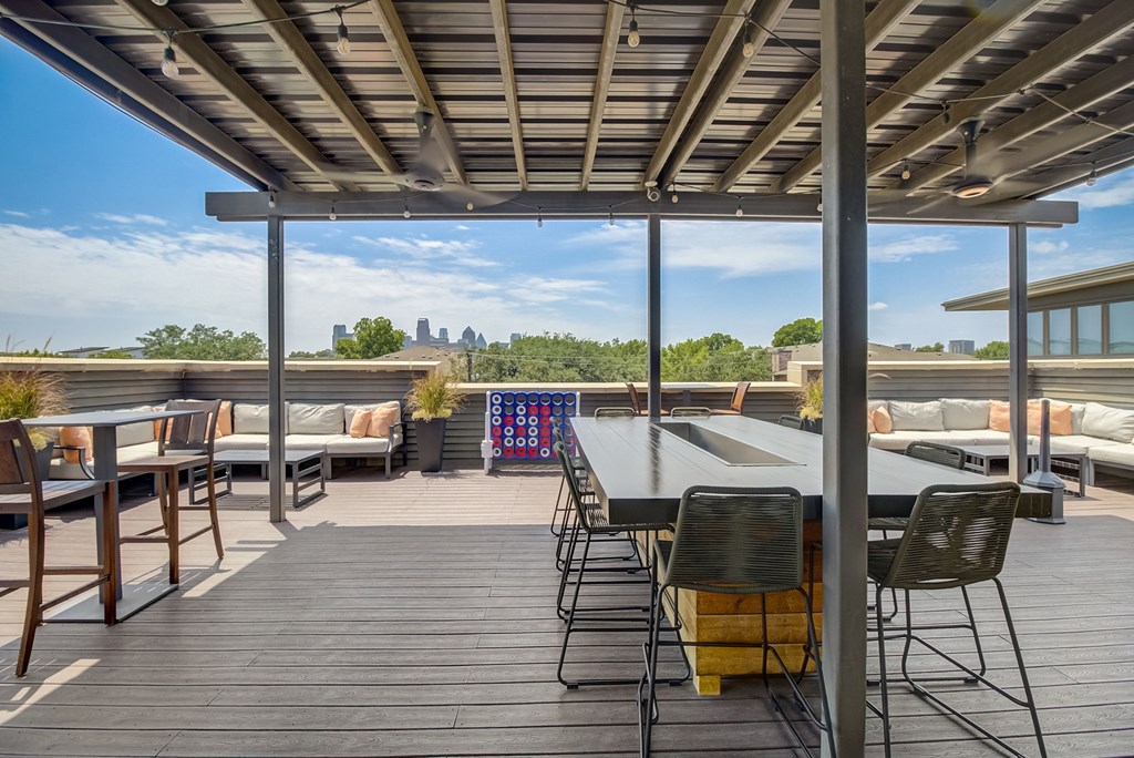 a rooftop deck with a table and chairs and a view of the city