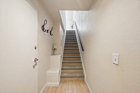 A staircase with a light switch on the wall.