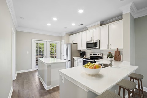 a white kitchen with a bowl of fruit on the counter