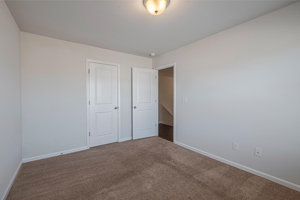 a bedroom with white walls and carpet and two doors