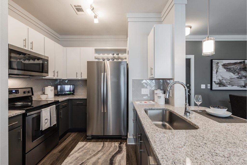 a kitchen with granite counter tops and a stainless steel refrigerator