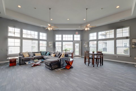 A spacious living room with a grey couch and a grey floor.
