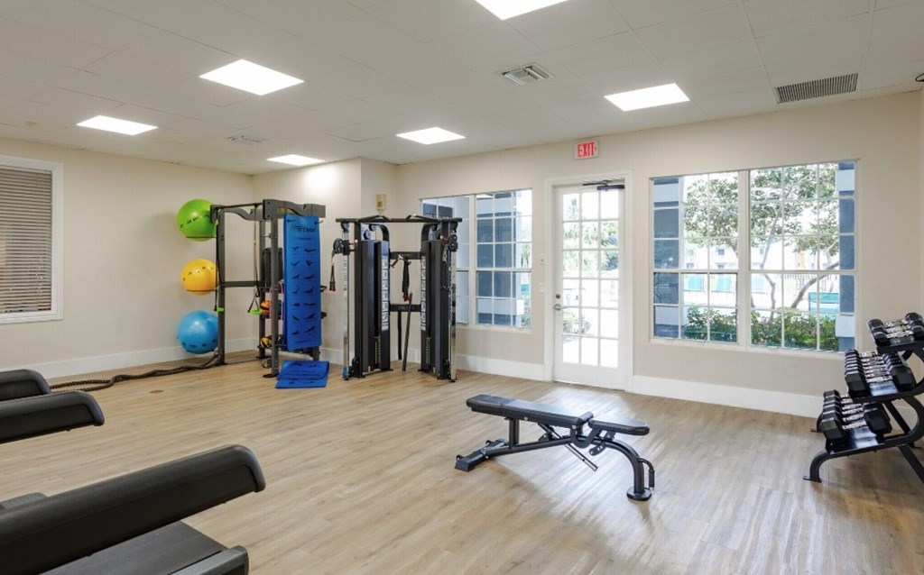 A gym with a variety of equipment including a bench, weights, and a ball.