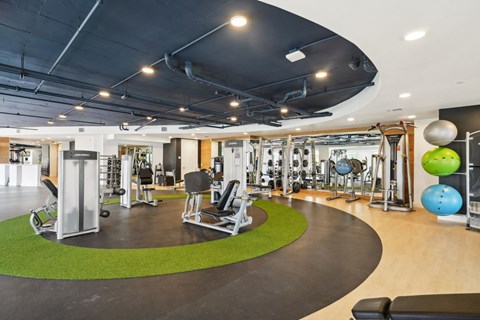 A gym with a variety of equipment including weights and exercise balls.