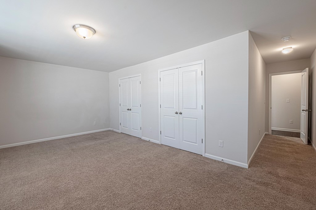 a bedroom with three closets and a carpeted floor