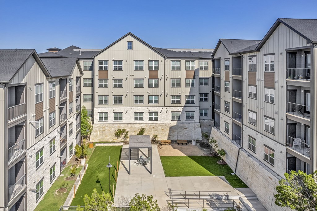 an aerial view of an apartment building with a courtyard and green grass