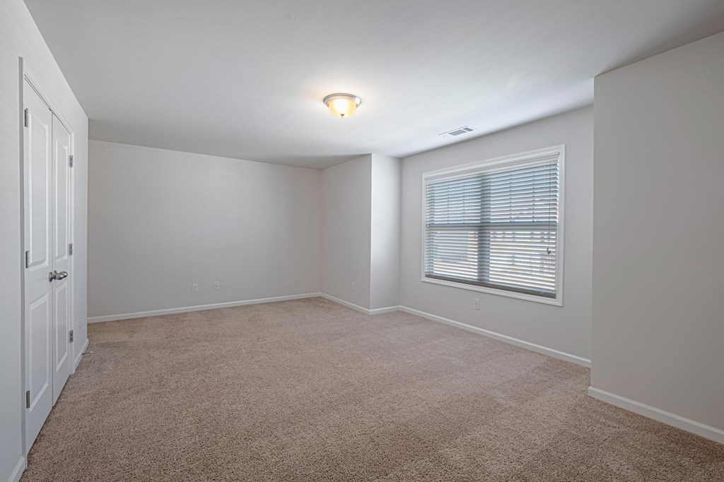 an empty living room with a large window and carpet