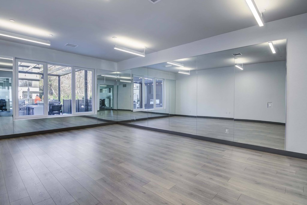 A spacious room with wooden floors and large windows.