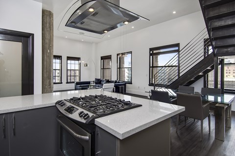 A modern kitchen with a stove top oven and a black staircase.