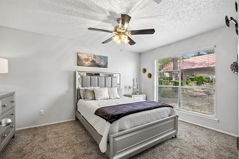 A bedroom with a large bed and a ceiling fan.