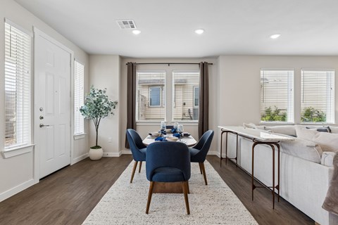 A dining room with a table set for two and a couch in the background.