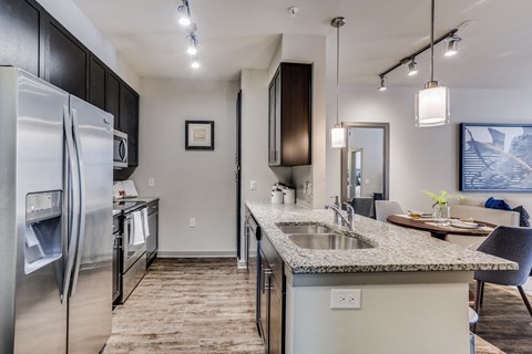 an open kitchen with stainless steel appliances and a granite counter top