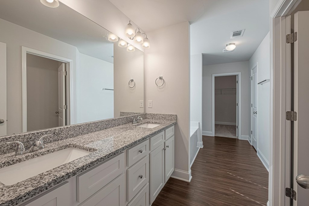 a bathroom with two sinks and a long hallway with a door to a closet