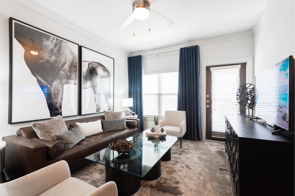 a living room with a brown leather couch and a glass coffee table