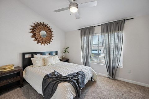A bedroom with a bed, a ceiling fan, and a mirror on the wall.