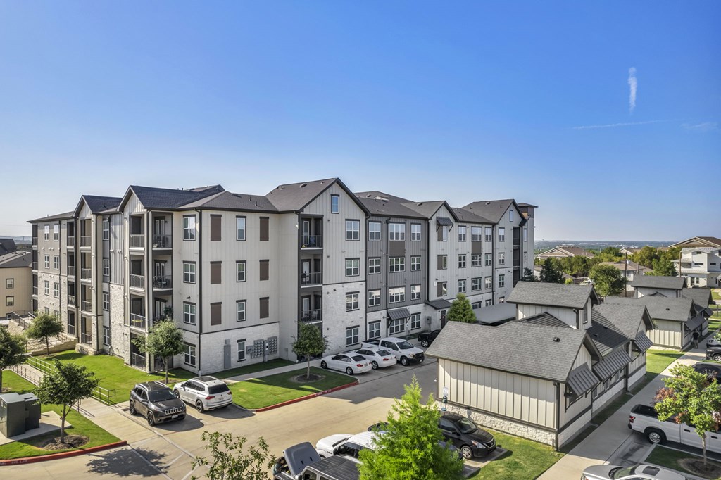an aerial view of an apartment building with cars parked in a parking lot