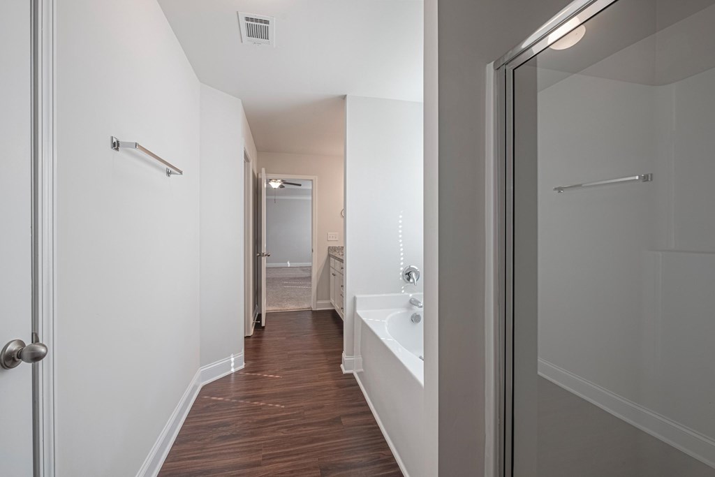 a bathroom with a shower and a bath tub and a hallway with a door open
