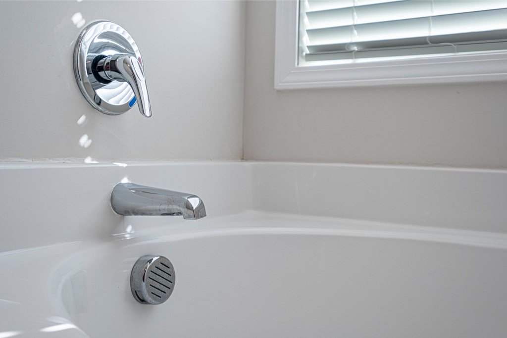 a bathroom with a tub and a faucet and a window
