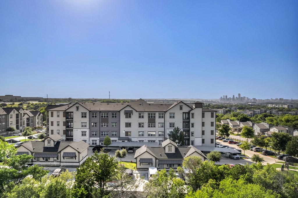 an aerial view of an apartment building with trees and a city in the background