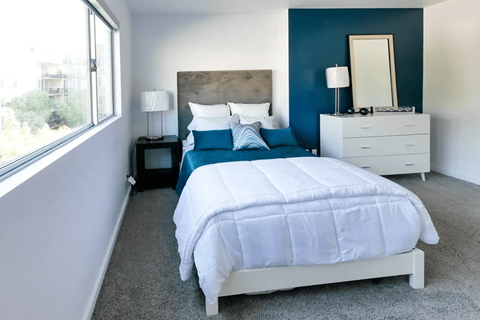 A bedroom with a white bed and a blue headboard.