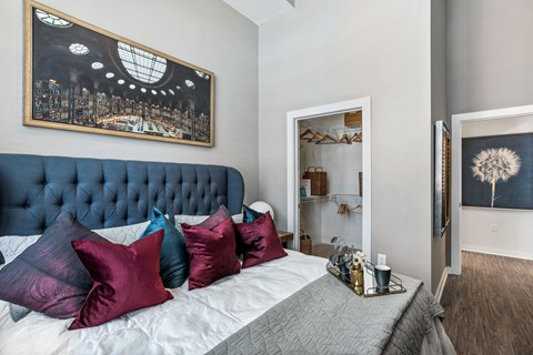 Three-Bedroom Apartments in
Germantown, Nashville, TN -
Peyton Stakes - Furnished
Bedroom with Hardwood-Inspired
Flooring, Large Bed, Nightstand
with Lamp, Framed Wall Art, and
Spacious Closet with Shelves.