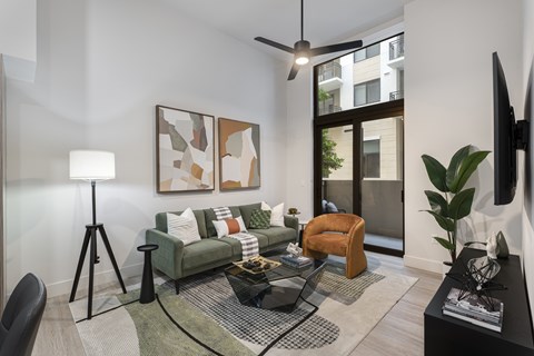 A living room with a green couch, a black coffee table, and a painting on the wall.