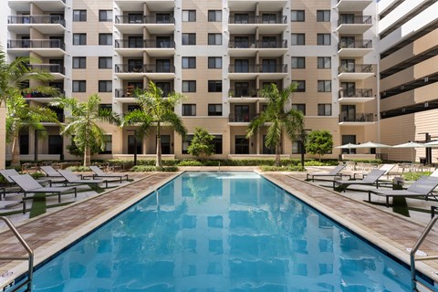 A large swimming pool in front of a multi-story apartment building.