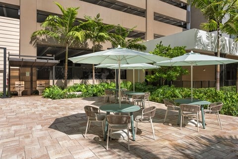 A patio with tables and chairs and umbrellas.