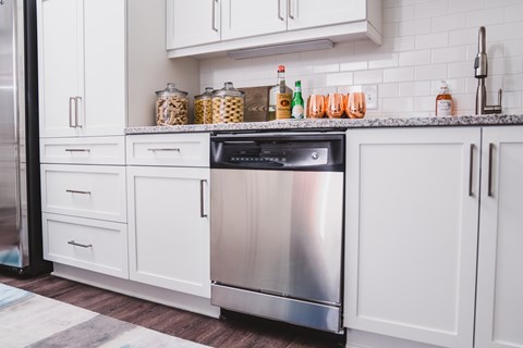 A modern kitchen with white cabinets and a stainless steel dishwasher.