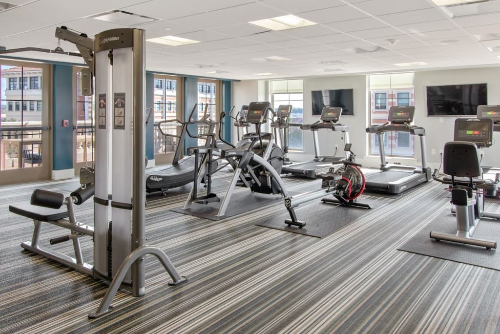 a gym with various exercise equipment in a room with windows