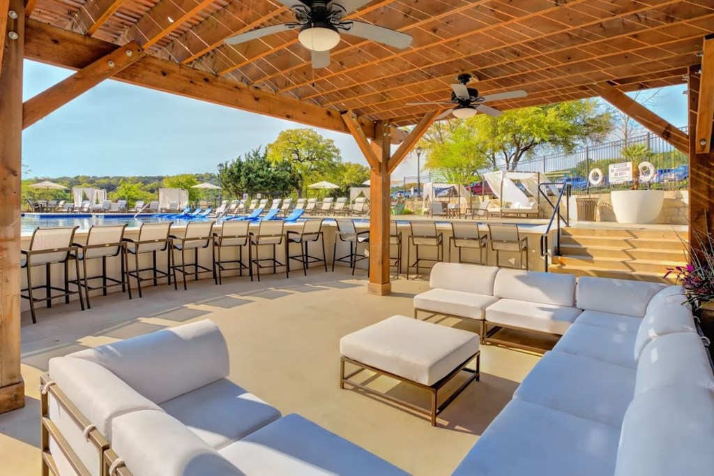 a patio with couches and chairs and tables at a pool