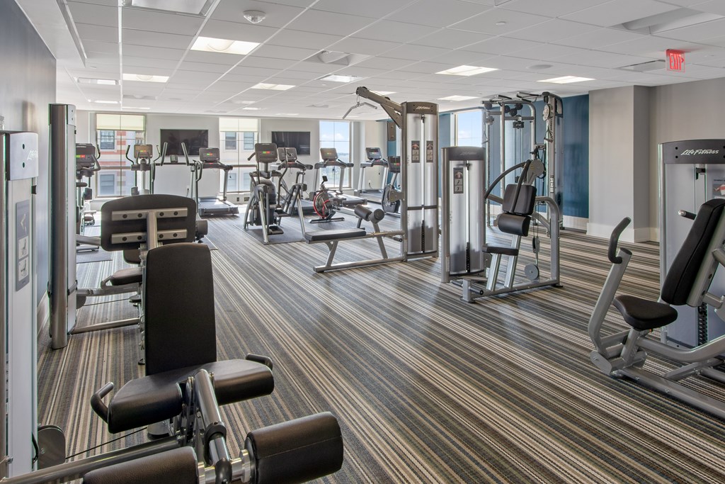 a gym with various cardio machines and weights on a carpeted floor
