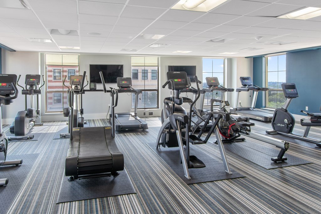 a gym with various exercise equipment in a room with windows