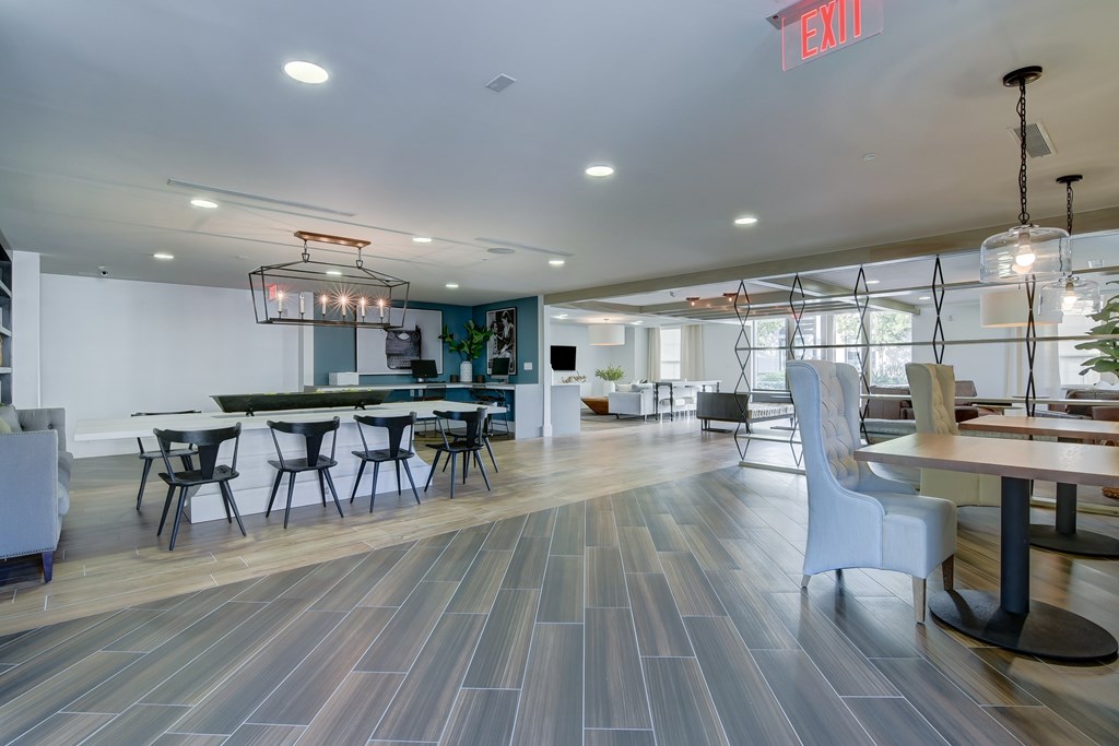 a dining room with tables and chairs and a bar and a living room with chairs